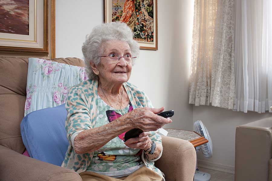 Elderly woman watches the TV in her home